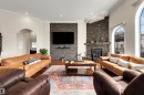 Stone veneer fireplace with an integrated mantel, wood-finish flooring, recessed lighting, arched doorways, and arched windows - 282 Ozerna Road Nw, Edmonton, AB 
