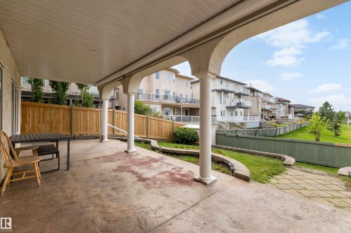 Covered patio featuring decorative columns, stamped concrete flooring, and direct access to the landscaped yard with a wooden privacy fence - 282 Ozerna Road Nw, Edmonton, AB 
