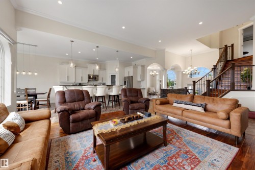 Expansive living area featuring wood-finish flooring, recessed lighting, and a grand staircase with dark wood railings - 282 Ozerna Road Nw, Edmonton, AB 