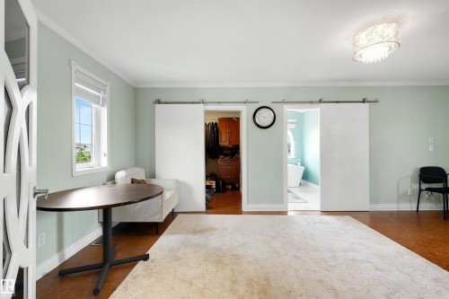 Window with white trim, wood-finish flooring, white barn doors, and overhead decorative lighting - 282 Ozerna Road Nw, Edmonton, AB 
