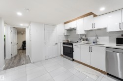 White tiled flooring, white cabinetry with wood-finish accents, stainless steel appliances, and recessed lighting - 