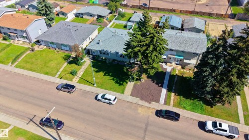 Gable roofline, mature trees, front yard with green lawn, paved sidewalk, and established neighborhood setting - 13435 101 Street Nw, Edmonton, AB 