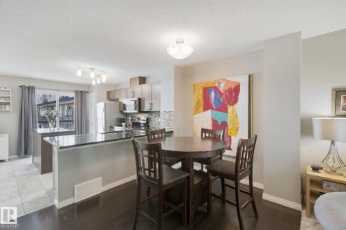 Open-concept kitchen featuring dark countertops, light wood-finish cabinetry, and a subway tile backsplash - #58 4029 Orchards Dr Sw, Edmonton, AB 