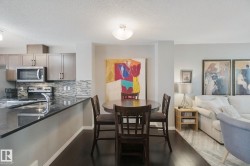 Kitchen featuring dark cabinetry, stainless steel appliances, a multi-tone tile backsplash, and dark countertops - 