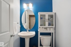 Pedestal sink with chrome faucet, wall-mounted oval mirror, and overhead vanity lighting - 