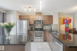 Kitchen featuring stainless steel appliances, dark stone countertops, wood-finish cabinetry, and a patterned tile backsplash - 