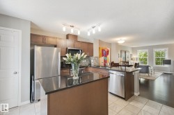 Kitchen featuring stainless steel appliances, dark wood-finish cabinetry, a central island with a dark countertop, and tile flooring - 
