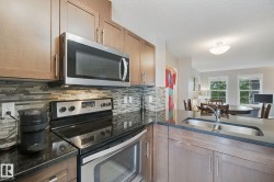 Kitchen featuring wood-finish cabinetry, stainless steel appliances, granite-style countertops, mosaic tile backsplash, and an undermount sink - 