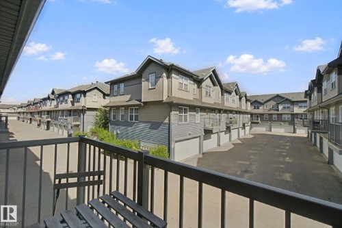 Balcony with metal railing overlooking a paved parking area - #58 4029 Orchards Dr Sw, Edmonton, AB 