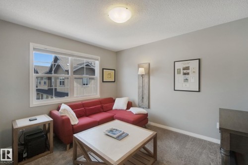 Neutral wall color, carpeted flooring, large window, and ceiling-mounted light fixture - #58 4029 Orchards Dr Sw, Edmonton, AB 