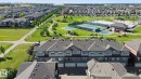 Multi-unit residential structures with attached garages, surrounded by extensive green spaces, paved pathways, and recreational courts - #58 4029 Orchards Dr Sw, Edmonton, AB 