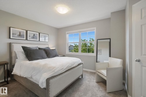 Carpeted bedroom featuring a flush mount ceiling light, multiple-pane window, and painted interior door - #58 4029 Orchards Dr Sw, Edmonton, AB 