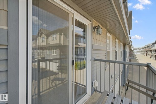Sliding glass door access to an exterior balcony featuring metal railings and a mounted light fixture - #58 4029 Orchards Dr Sw, Edmonton, AB 