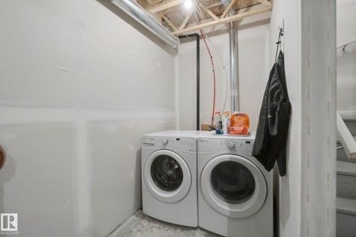 Dedicated laundry area with concrete flooring, exposed ceiling joists, and utility piping - #58 4029 Orchards Dr Sw, Edmonton, AB 