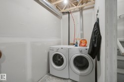 Dedicated laundry area with concrete flooring, exposed ceiling joists, and utility piping - 