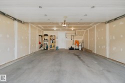 Spacious garage featuring a concrete floor, exposed framing, and an interior access door - 