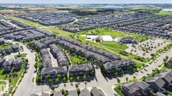 Expansive community featuring residential buildings, a large asphalt parking area, and green spaces with walking paths - 