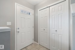 Entryway with tile flooring, a white paneled door featuring an upper window, and bi-fold closet doors - 