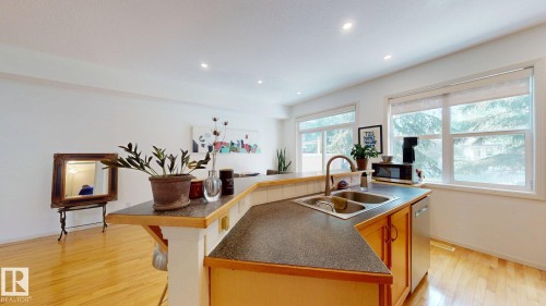 Kitchen island with a dual basin stainless steel sink, wood-finish cabinetry, and recessed lighting - 9846 112 Street Nw, Edmonton, AB 