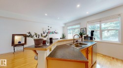Kitchen island with a dual basin stainless steel sink, wood-finish cabinetry, and recessed lighting - 