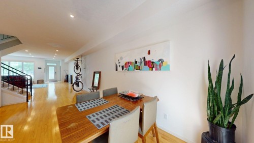Hardwood flooring throughout, recessed ceiling lighting, and a modern staircase with black metal railings - 9846 112 Street Nw, Edmonton, AB 