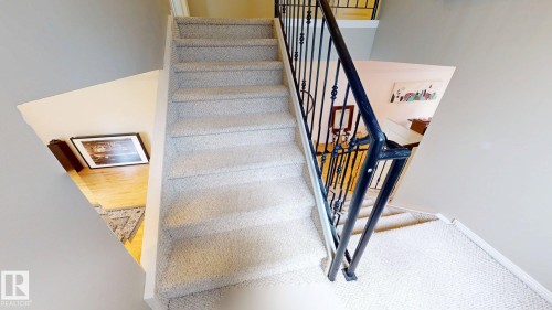 Carpeted staircase with wrought iron balusters - 9846 112 Street Nw, Edmonton, AB 