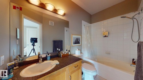 Full vanity with integrated sink, wood-finish cabinetry, and speckled countertop - 9846 112 Street Nw, Edmonton, AB 