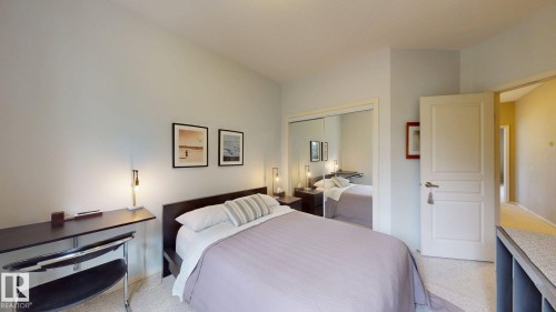 Bedroom featuring carpet flooring, mirrored closet doors, a paneled interior door, and light-toned walls - 9846 112 Street Nw, Edmonton, AB 