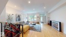 Open-concept living area featuring light wood-finish flooring, recessed lighting, and large windows - 9846 112 Street Nw, Edmonton, AB 