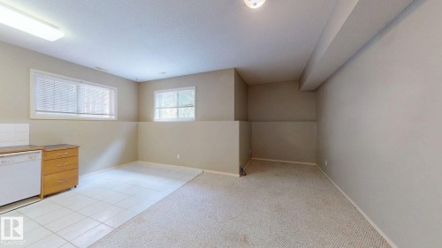 Two windows providing natural light, kitchen area with wood-finish cabinetry, tile flooring, and carpeted area - 9846 112 Street Nw, Edmonton, AB 