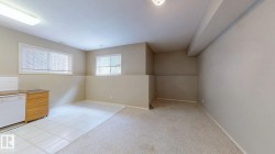 Two windows providing natural light, kitchen area with wood-finish cabinetry, tile flooring, and carpeted area - 