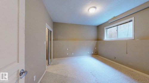 Carpeted room featuring a window, built-in ceiling light, and mirrored closet doors - 9846 112 Street Nw, Edmonton, AB 