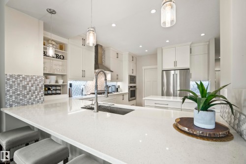 Expansive kitchen island with a light-toned countertop, integrated sink, and pull-down faucet - 5966 Edmonds Crescent Nw, Edmonton, AB - Indoor Photo Showing Kitchen With Upgraded Kitchen