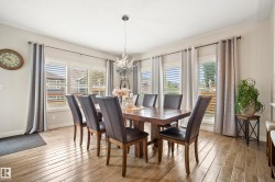 Dining area featuring light wood-finish flooring, multiple windows with horizontal blinds, and a contemporary chandelier - 
