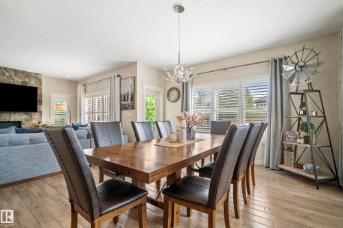 Dining area featuring wood-finish flooring, a contemporary chandelier, and window shutters - 5966 Edmonds Crescent Nw, Edmonton, AB - Indoor Photo Showing Dining Room