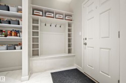 Entryway mudroom featuring built-in bench seating, storage cubbies, coat hooks, and an adjacent pantry with shelving - 