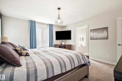 Bedroom featuring soft gray walls, neutral carpet flooring, and a large window with horizontal blinds - 5966 Edmonds Crescent Nw, Edmonton, AB - Indoor Photo Showing Bedroom