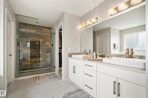 Bathroom featuring a dual vanity with rectangular vessel sinks, white cabinetry, and a mosaic tile backsplash - 5966 Edmonds Crescent Nw, Edmonton, AB - Indoor Photo Showing Bathroom