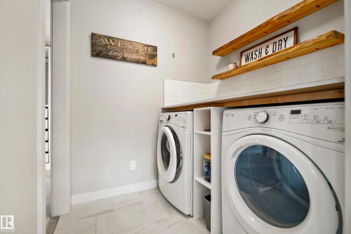 Dedicated laundry area featuring white appliances, a wood-finish countertop, and white subway tile backsplash - 5966 Edmonds Crescent Nw, Edmonton, AB - Indoor Photo Showing Laundry Room