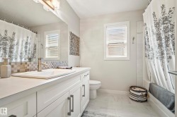 Bathroom featuring a white vanity with integrated sink, brushed nickel faucet, and a mosaic tile backsplash - 