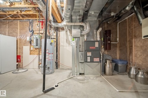 Dedicated utility area featuring a water heater, furnace, and exposed ductwork - 5966 Edmonds Crescent Nw, Edmonton, AB - Indoor Photo Showing Basement