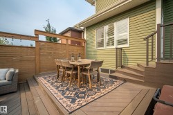 Multi-level composite deck featuring a slatted wood privacy screen and integrated string lighting - 