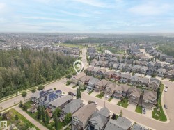 Aerial overview of a residential area featuring numerous detached homes with varied architectural styles, mature landscaping, and an extensive tree line bordering the neighborhood - 