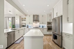 Modern kitchen featuring white cabinetry, quartz countertops, a central island, and stainless steel appliances - 