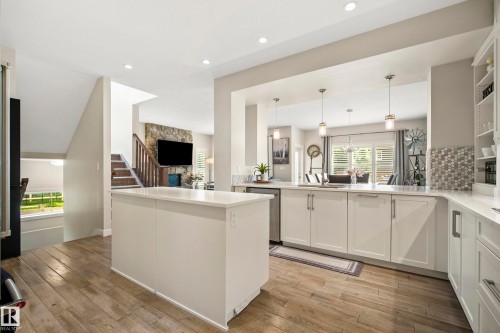Spacious kitchen featuring a central island, white shaker-style cabinetry, light-toned countertops, and wood-finish flooring - 5966 Edmonds Crescent Nw, Edmonton, AB - Indoor Photo Showing Kitchen With Upgraded Kitchen