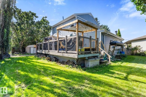 Expansive backyard with a manicured lawn, multi-level wood deck, and a detached storage shed - 6054 107A Street Nw, Edmonton, AB 