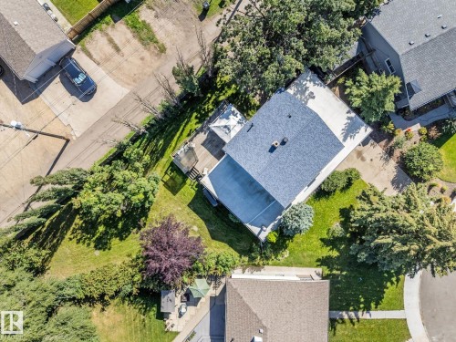 Aerial view of a contemporary home featuring a newly installed asphalt shingle roof, expansive manicured lawn, and mature landscaping with established trees throughout the property - 6054 107A Street Nw, Edmonton, AB 