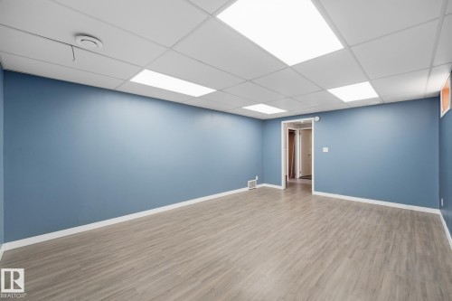 Spacious room featuring wood-finish flooring, drop ceiling with recessed lighting, and a neutral wall color - 13304 63 Street Nw, Edmonton, AB 
