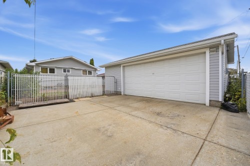 Detached garage with horizontal siding, concrete driveway, and chain-link fencing - 13304 63 Street Nw, Edmonton, AB 