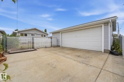 Detached garage with horizontal siding, concrete driveway, and chain-link fencing - 